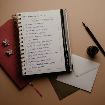 A red and white notebook with New Year's Resolutions written in script handwriting