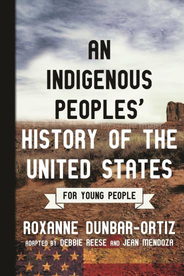 book cover for An Indigenous Peoples' History of the United States, for Young People, featuring a photograph of a southwestern landscape, with a majestic expanse of scrubland baking under the sun and leading towards a tall, vertical rock formation in the distance.  A transparent American flag tints and overlays the bottom strip of the image.