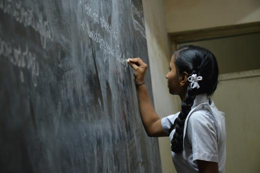 Girl writes on chalkboard in another language