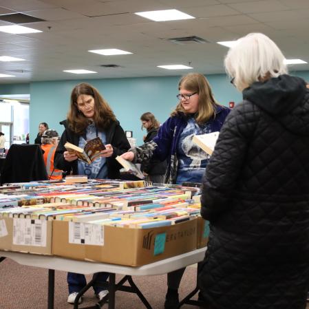 Three women look through BCL Friends books for sale