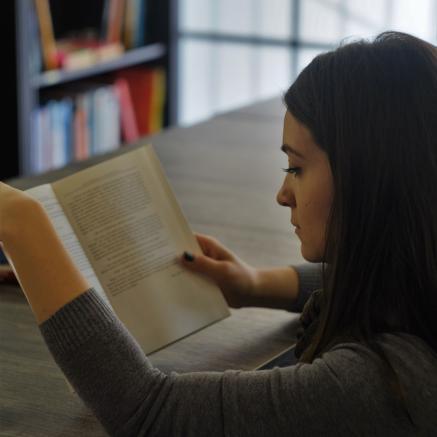 A young woman reads at a table.