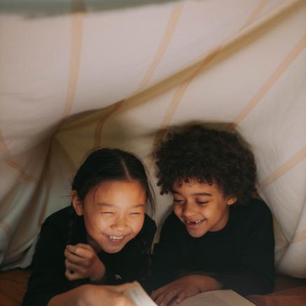 Two children giggle over a book.