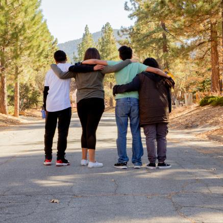 Four teens walk down a wooded path.