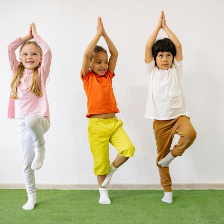 Kids do yoga on green grass rug