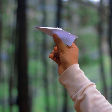 A child's hand holding a paper airplane