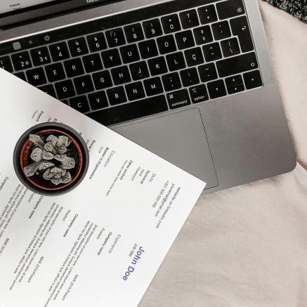 A resume document next to a laptop computer.