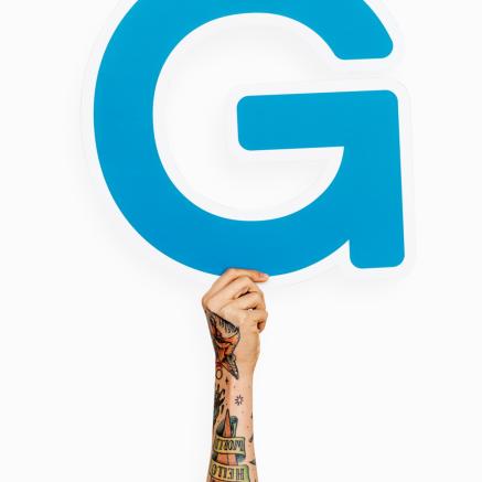 A tattooed arm holds up the Google G.