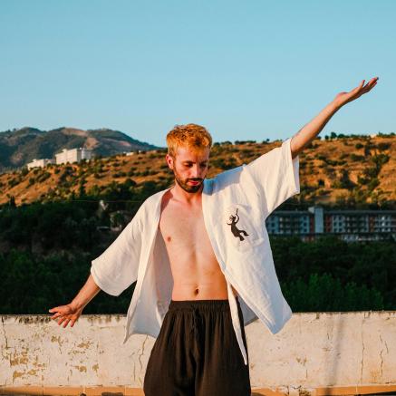 A man stands on the beach wearing a Tai Chi uniform.