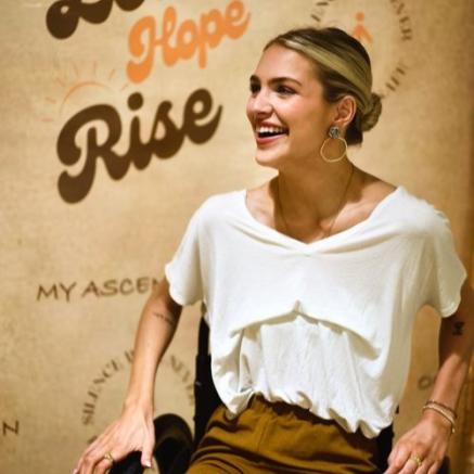 Emma Benoit, suicide survivor, smiles and laughs in front of her documentary film poster