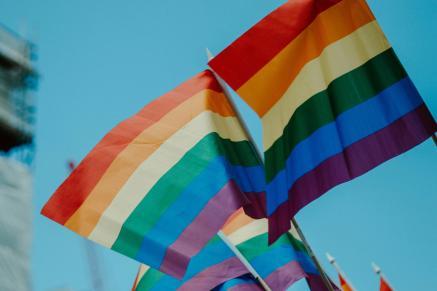 Rainbow Pride flags against a blue sky.