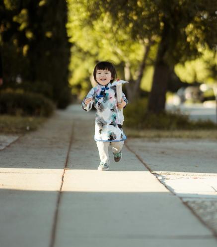 A young girl smiles while walking towards the camera.