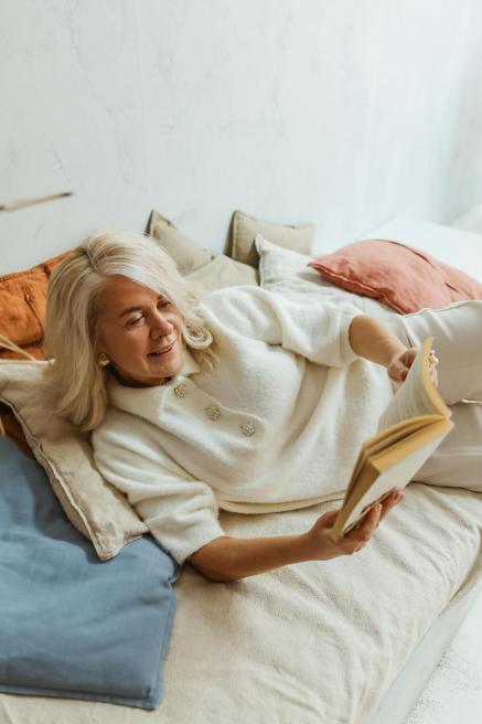 A woman with white hair reads a book.