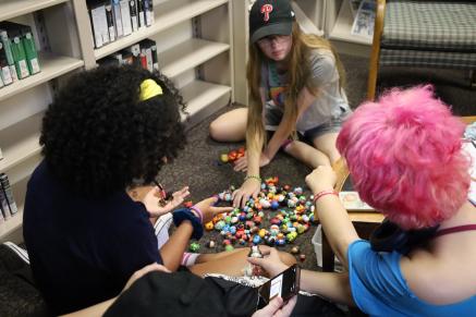 Three teens play with small Disney figurines at Riverton Anime Club