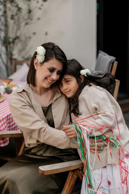 A mother hugs her daughter during an outdoor celebration.