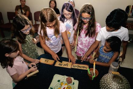 Tweens at Evesham's Harry Potter Escape room stand around a table with some clues on it