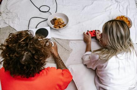 Two people lay on their stomachs on blankets with gaming controllers