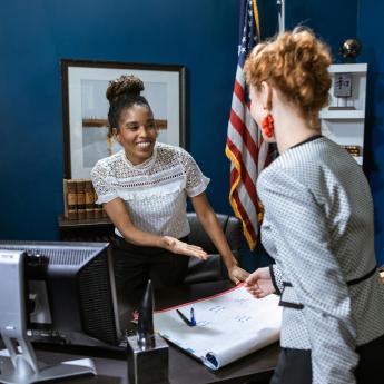 Women shake hands over a desk