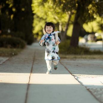 A young girl smiles while walking towards the camera.