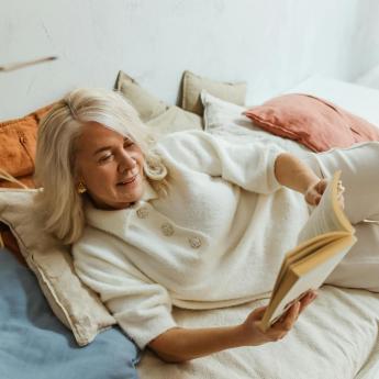 A woman with white hair reads a book.