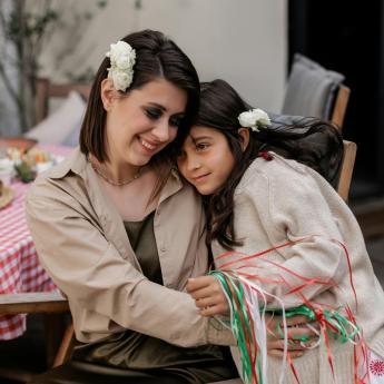 A mother hugs her daughter during an outdoor celebration.