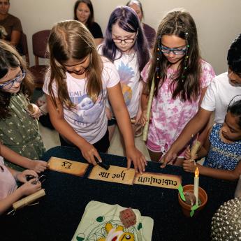 Tweens at Evesham's Harry Potter Escape room stand around a table with some clues on it